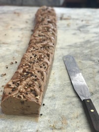 a long piece of chocolate ice cream with a knife next to it